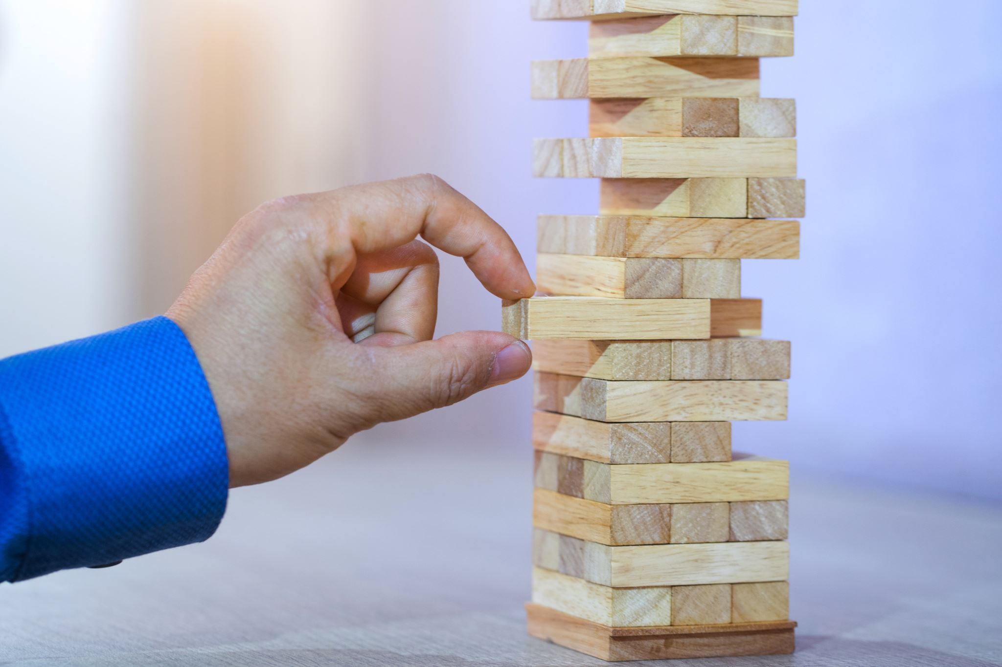 Geschäftsmann-zieht-einen-Block-vom-Jenga-Turm-ab